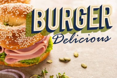 fresh bagel with ham near burger delicious lettering on textured surface clipart