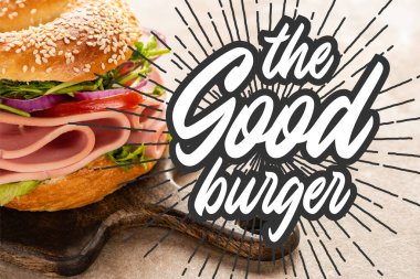 Lezzetli simit, ahşap kesim tahtasının üzerinde, desenli yüzeydeki hamburgerin yanında.