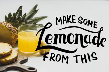 Tahta kesim tahtasının yanında dilimlenmiş meyvenin yanında taze ananas suyu beyaz harflerle limonata yap. 