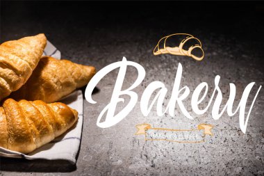 fresh croissants on towel near bakery and coffee lettering on concrete grey surface  clipart