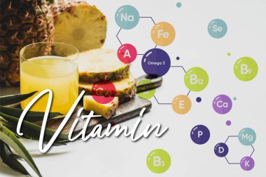 Bardakta taze ananas suyu ahşap kesme tahtasının yanında lezzetli meyve suyu ve beyaz üzerine vitamin harfleri. 