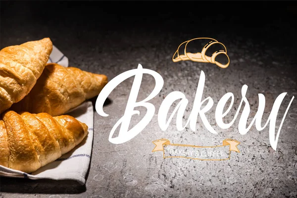 fresh croissants on towel near bakery and coffee lettering on concrete grey surface