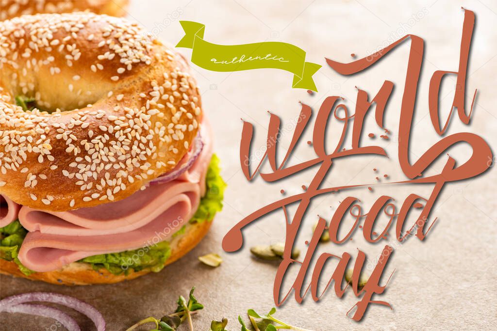 fresh bagel with ham near world food day lettering on textured surface
