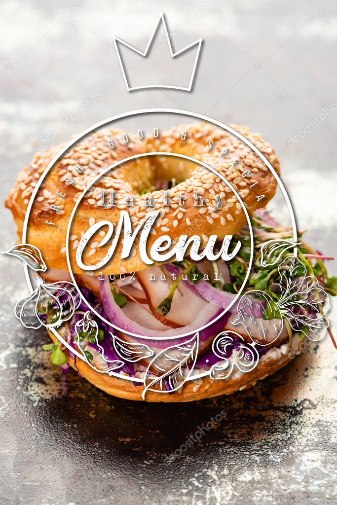 fresh bagel with meat, red onion, cream cheese and sprouts near healthy menu lettering on textured grey surface