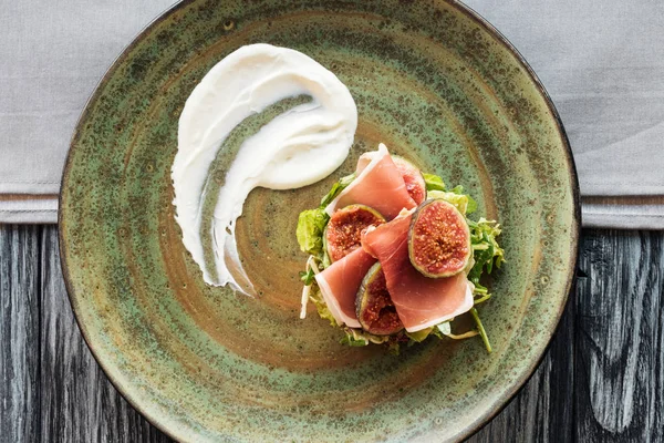 Close-up top view of delicious prosciutto with herbs and figs on plate — Stock Photo