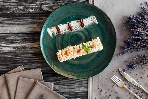 Вид на сладкий вкусный десерт с миндалем и мятой на тарелке на деревянном столе — стоковое фото