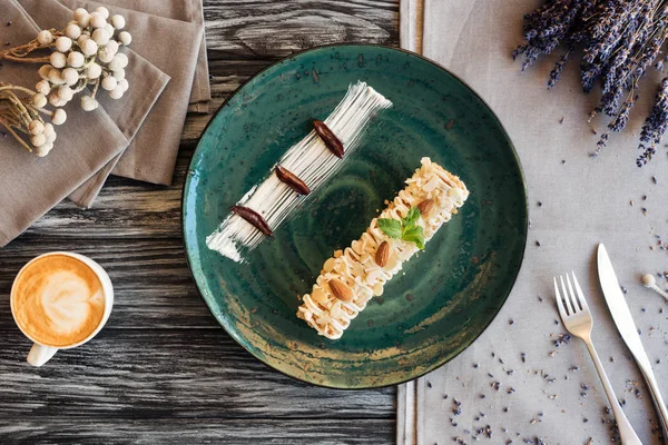 Vista superior de deliciosa sobremesa doce com amêndoas, xícara de cappuccino e garfo com faca na mesa — Fotografia de Stock