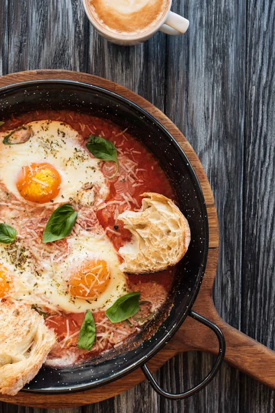 Vue du dessus de délicieux œufs frits dans une casserole et une tasse de café sur une table en bois — Photo de stock