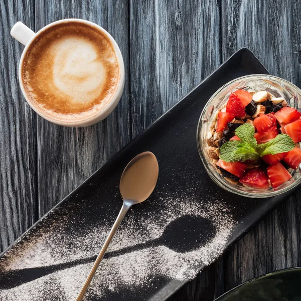 Top view of healthy fruity dessert, spoon and cup of coffee on wooden table — Stock Photo