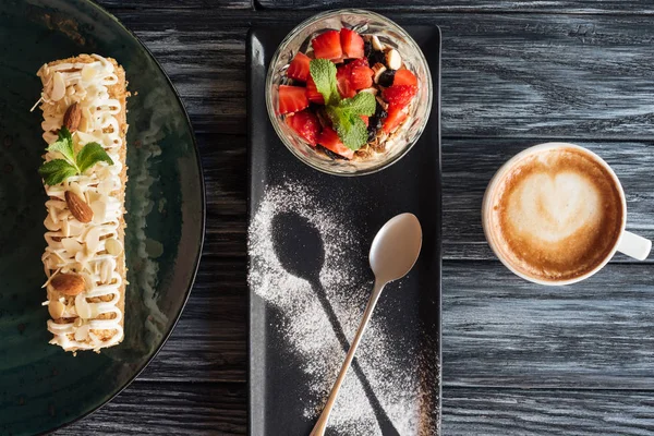 Vista superior de postres gourmet dulces y taza de café en la mesa de madera - foto de stock