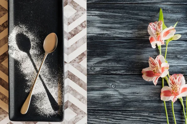 Vue du dessus de la cuillère avec de la poudre prête pour le dessert et de belles fleurs sur table en bois — Photo de stock