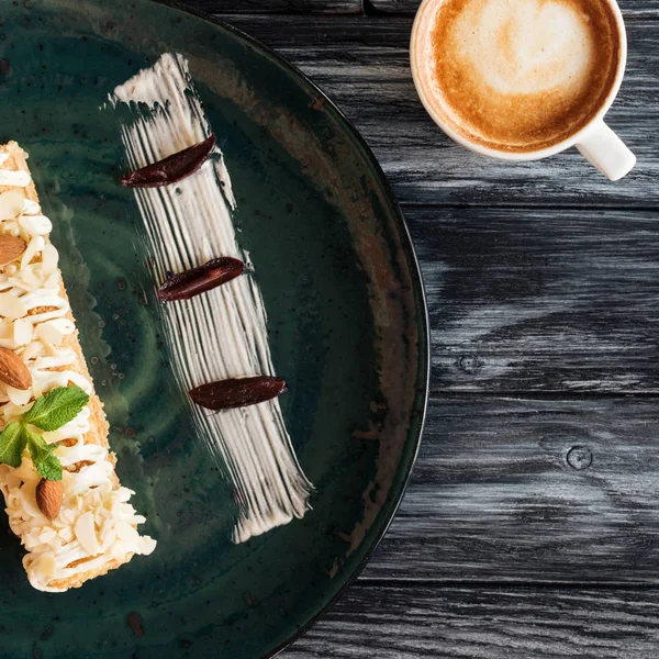 Vue rapprochée du délicieux dessert aux amandes et tasse de cappuccino sur table en bois — Photo de stock