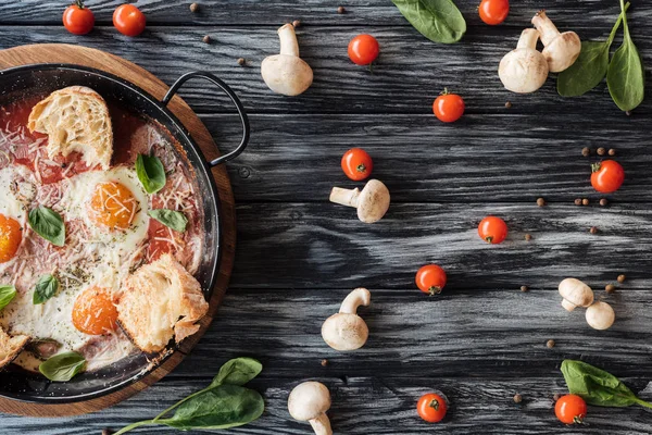 Blick von oben auf leckere Spiegeleier mit Käse und Brot und frischem Gemüse auf Holztisch — Stockfoto