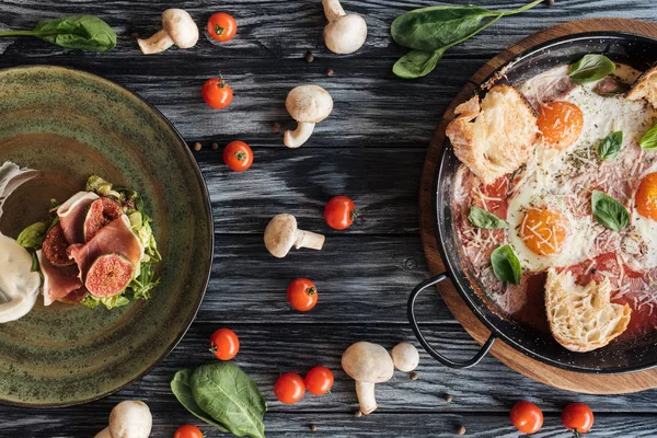 Vista superior de delicioso prosciutto, ovos fritos e legumes frescos na mesa de madeira — Fotografia de Stock