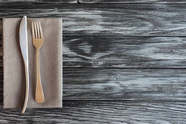 Vista superior de garfo e faca no guardanapo na mesa de madeira — Fotografia de Stock