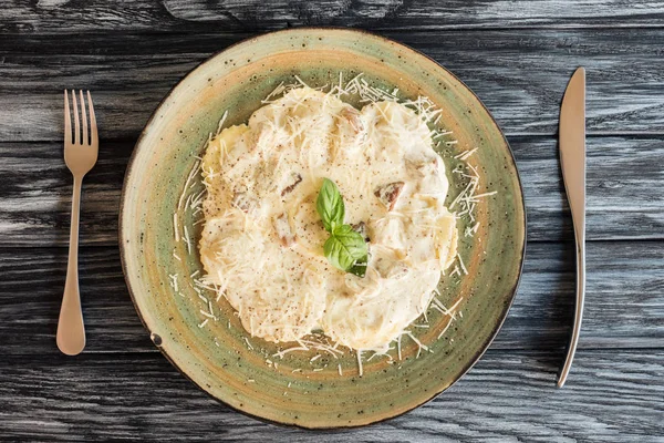 Delicioso ravioli italiano com queijo de ricota no prato e garfo com faca na mesa de madeira — Fotografia de Stock