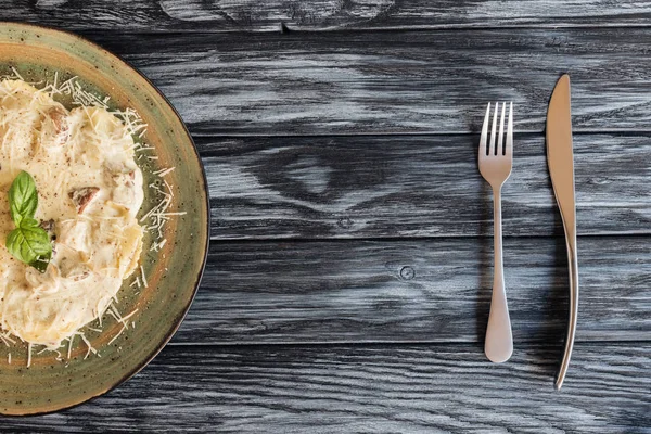 Delicious ravioli with spinach and ricotta cheese, fork and knife on wooden table — Stock Photo