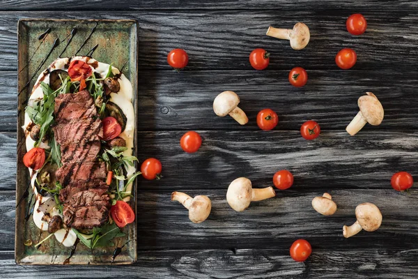 Vista superior de carne asada en rodajas gourmet con verduras en mesa de madera - foto de stock