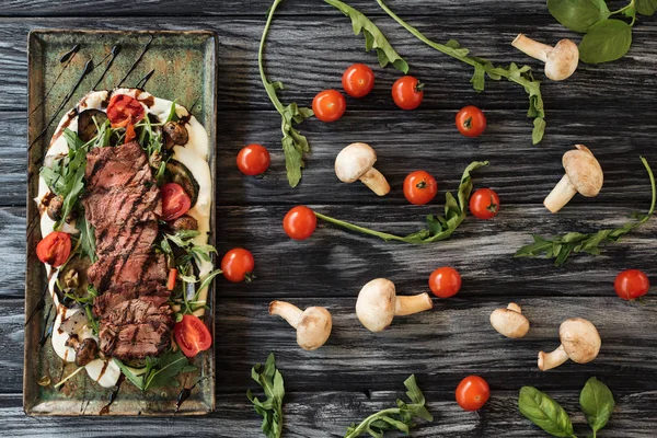 Vista superior de delicioso bife cozido fatiado com legumes na mesa de madeira — Fotografia de Stock