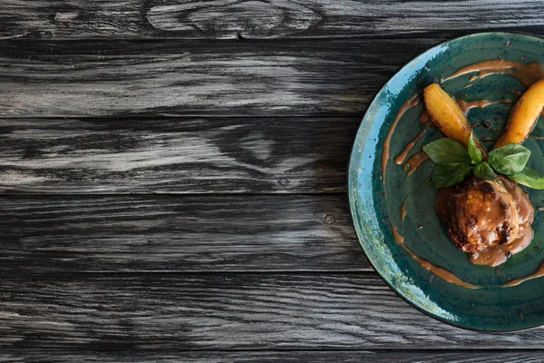 Top view of tasty cooked meat with basil leaves and sauce on plate on wooden table with copy space — Stock Photo