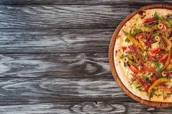 Top view of delicious pizza with vegetables, cheese and meat on wooden table with copy space — Stock Photo