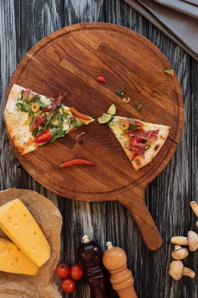 Вид зверху на скибочки смачної піци на дерев'яній дошці — стокове фото