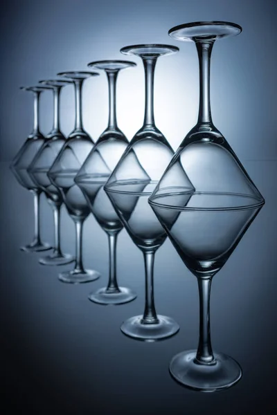 Fila di bicchieri da martini trasparenti su grigio con riflessi — Foto stock