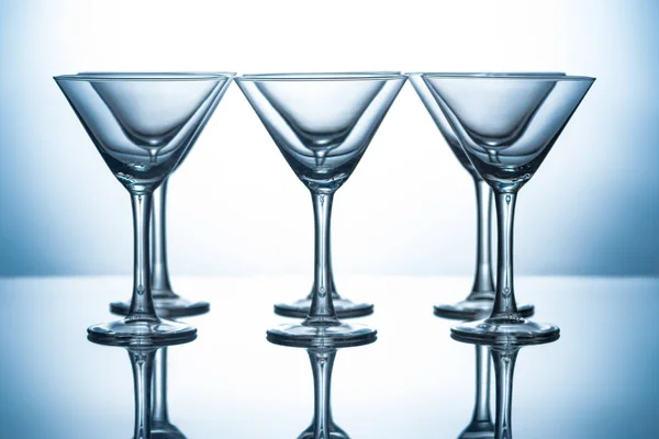 Row of transparent martini glasses on grey with reflections — Stock Photo