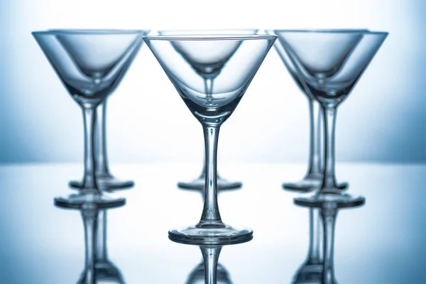 Row of empty martini glasses on grey with reflections — Stock Photo