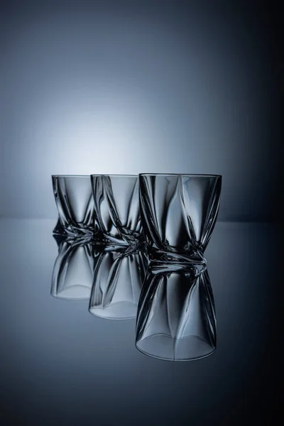 Row of empty cognac glasses on grey with reflections — Stock Photo