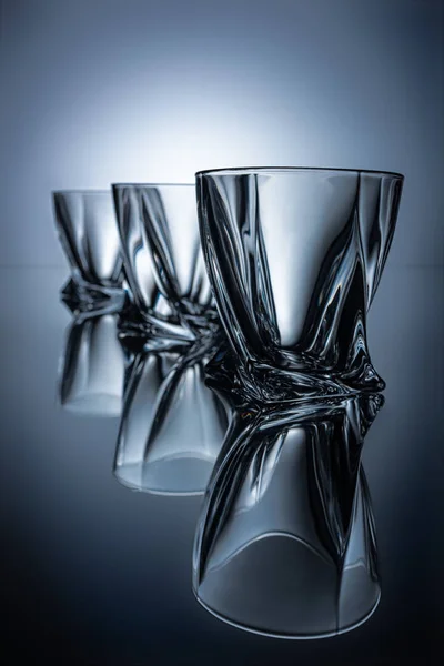 Rangée de trois verres à cognac sur fond gris avec reflets — Stock Photo