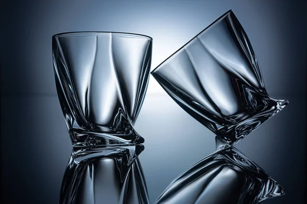 Deux verres à cognac vides transparents sur fond gris avec reflets — Photo de stock