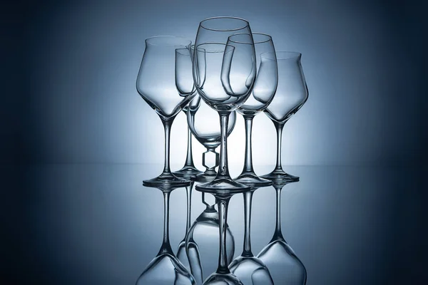 Silhouettes of different empty wine glasses with reflections, on grey — Stock Photo