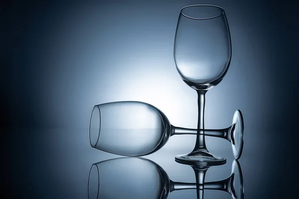 Silhouettes de verres à vin vides avec reflets, sur gris — Photo de stock