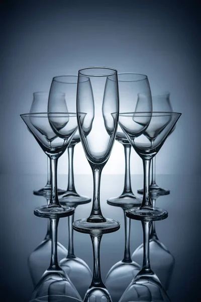 Silhouettes of different empty champagne, martini and wine glasses with reflections, on grey — Stock Photo