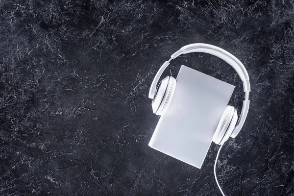 Top view of white book and headphones on grey tabletop — Stock Photo