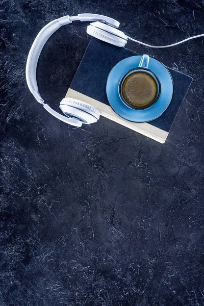 Vue du haut du livre, casque et tasse bleue avec café sur la table grise — Photo de stock