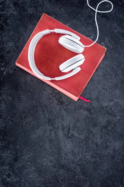 Top view of red book and white headphones on grey tabletop — Stock Photo