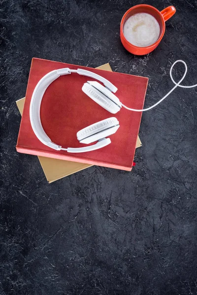 Top view of books, headphones and red cup of coffee with milk and on grey tabletop — Stock Photo