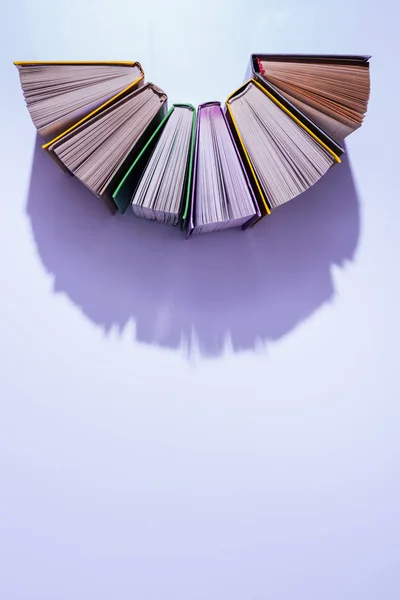 Top view of stack of books in half circle on violet table — Stock Photo