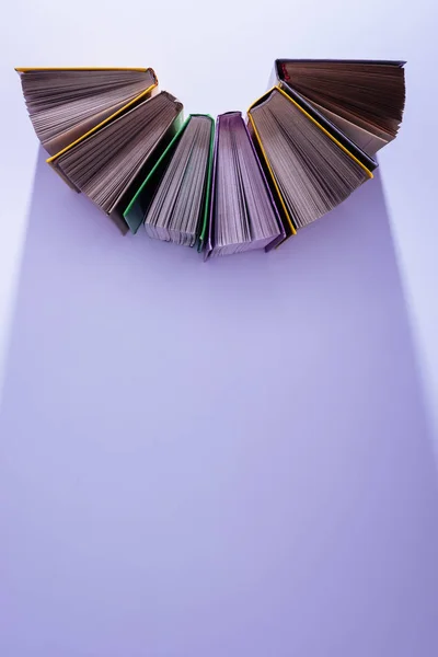 Підвищений вигляд стопки книг у півкола на фіолетовому столі — стокове фото