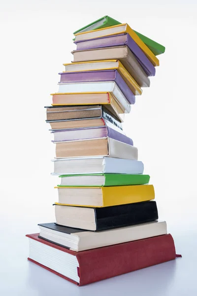 Pila de diferentes libros de colores en la mesa blanca - foto de stock