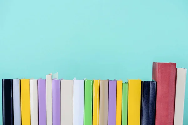 Fila de libros de colores aislados en azul - foto de stock