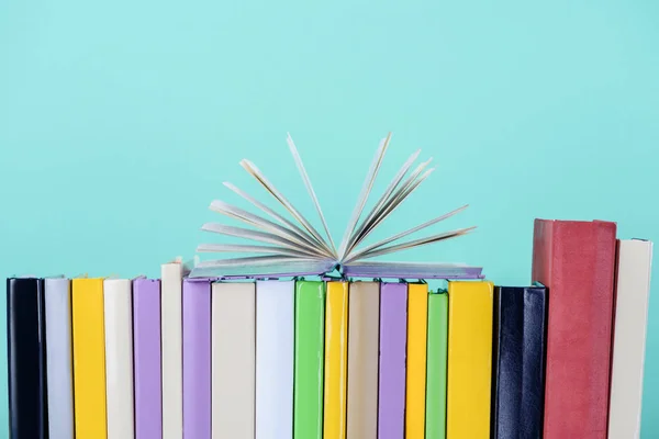 Open book on row of books isolated on blue — Stock Photo