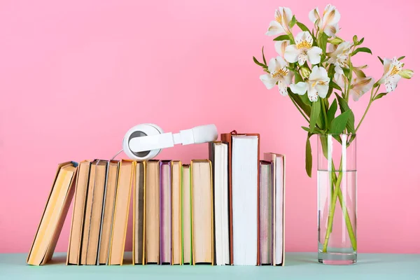 Навушники на ряду книг і квітів в склі на столі — стокове фото
