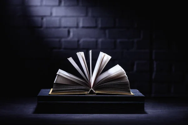 Aufgeschlagenes Buch auf dunkler Tischplatte mit Licht auf Seiten — Stockfoto