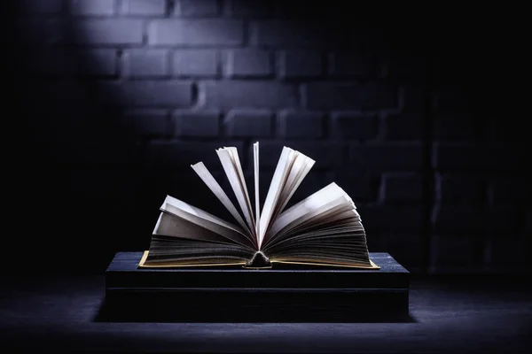 Libro abierto sobre mesa oscura con luz en las páginas - foto de stock