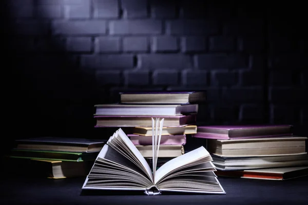 Open book in front of stack of books on dark surface — Stock Photo