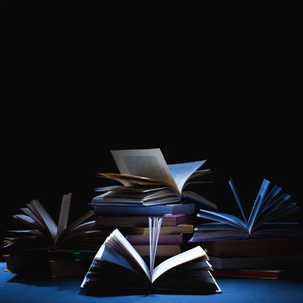 Stack of different books on dark tabletop on black — Stock Photo