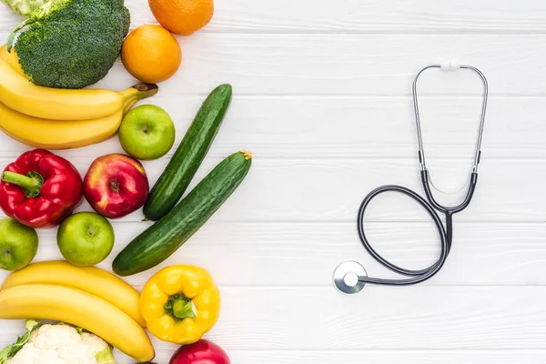 Top view of fresh fruits with vegetables and stethoscope on wooden surface — Stock Photo
